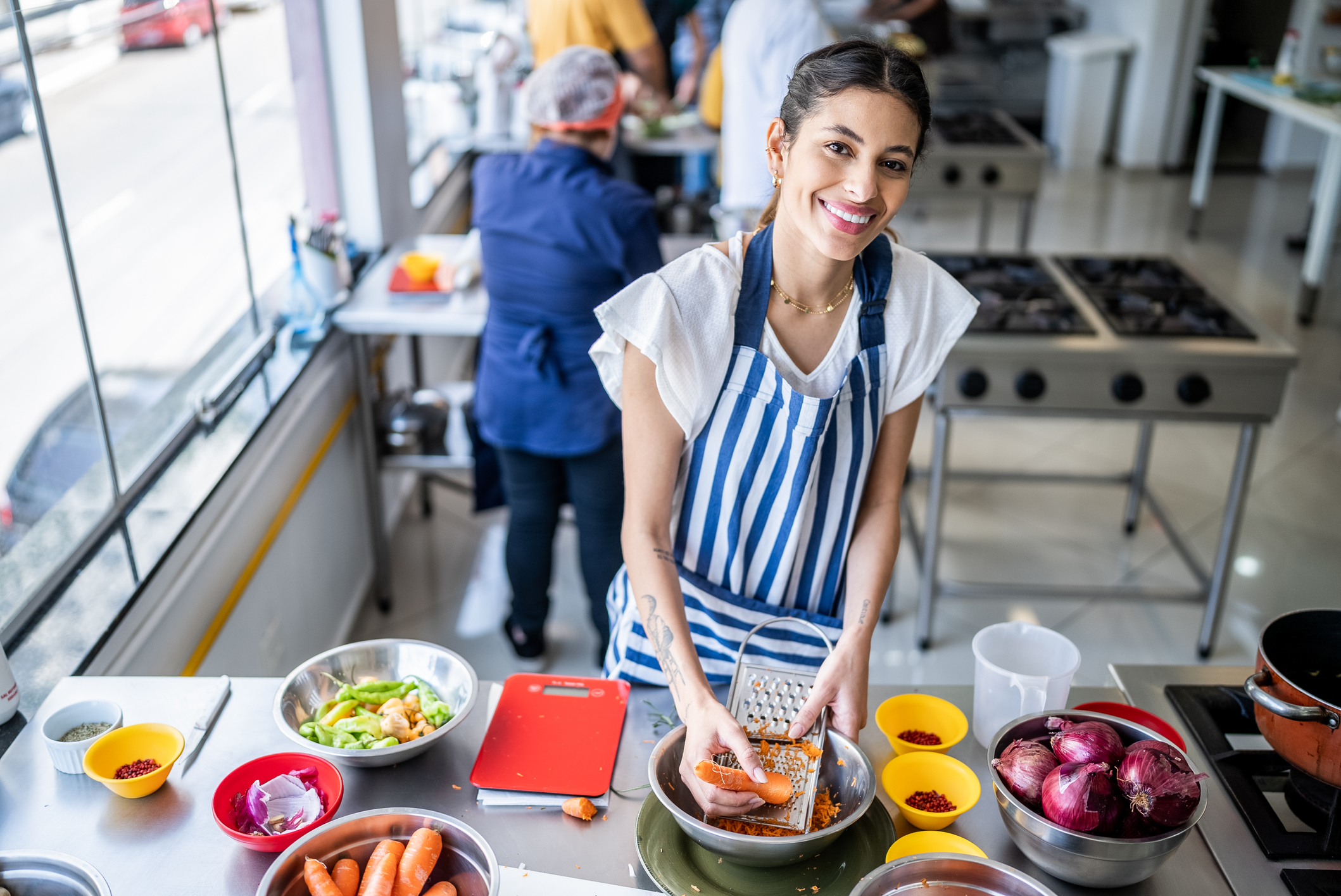 Portrait of a young woman grating carrot in the kitchen