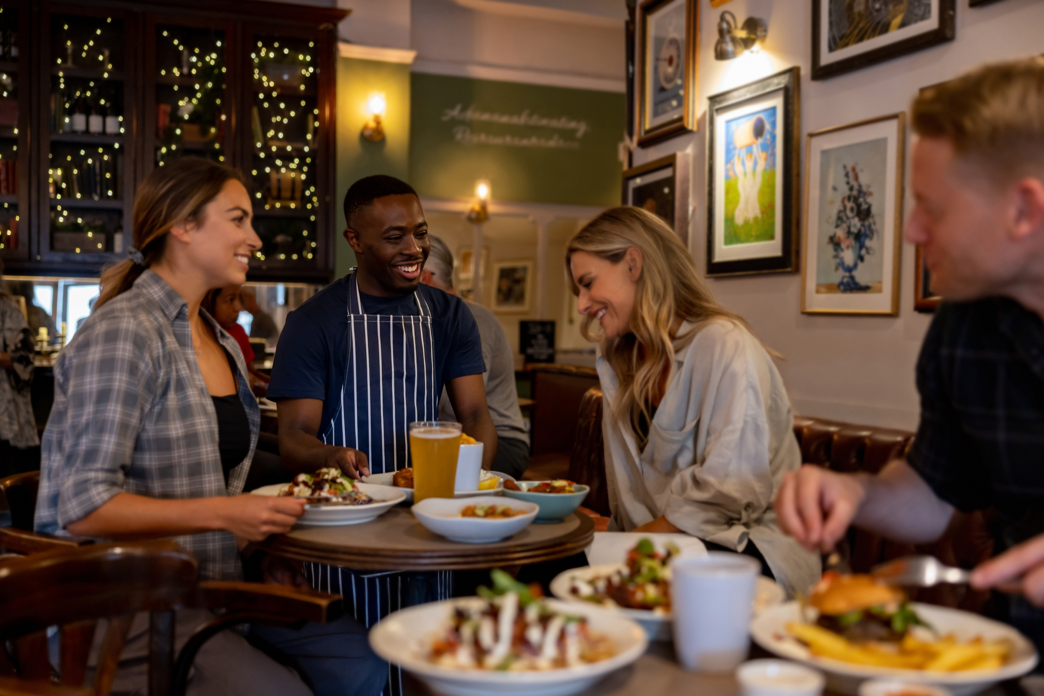 Waiter serving food to a group of friends at the pub