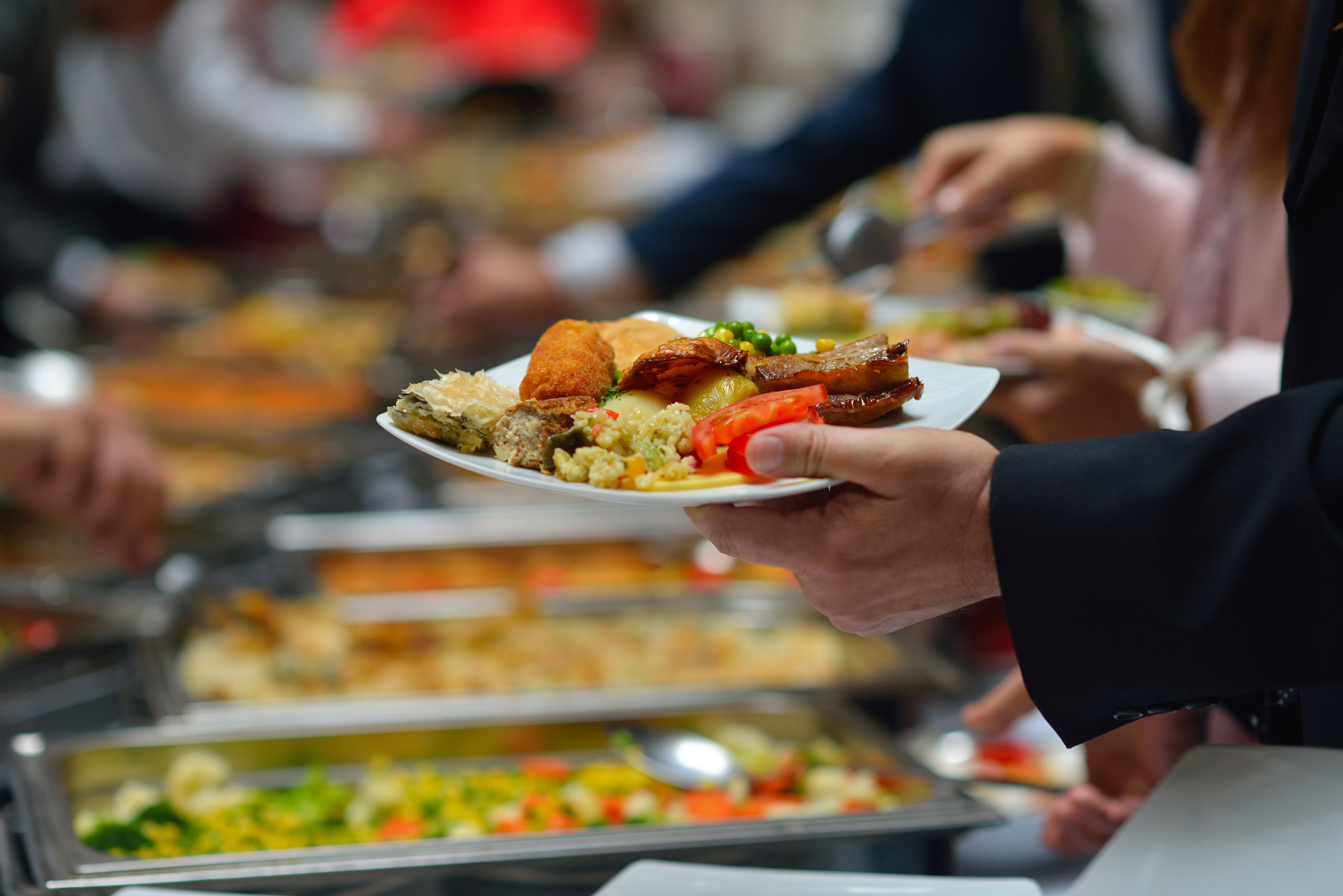 People in a buffet line with full plates People in a buffet line with full plates