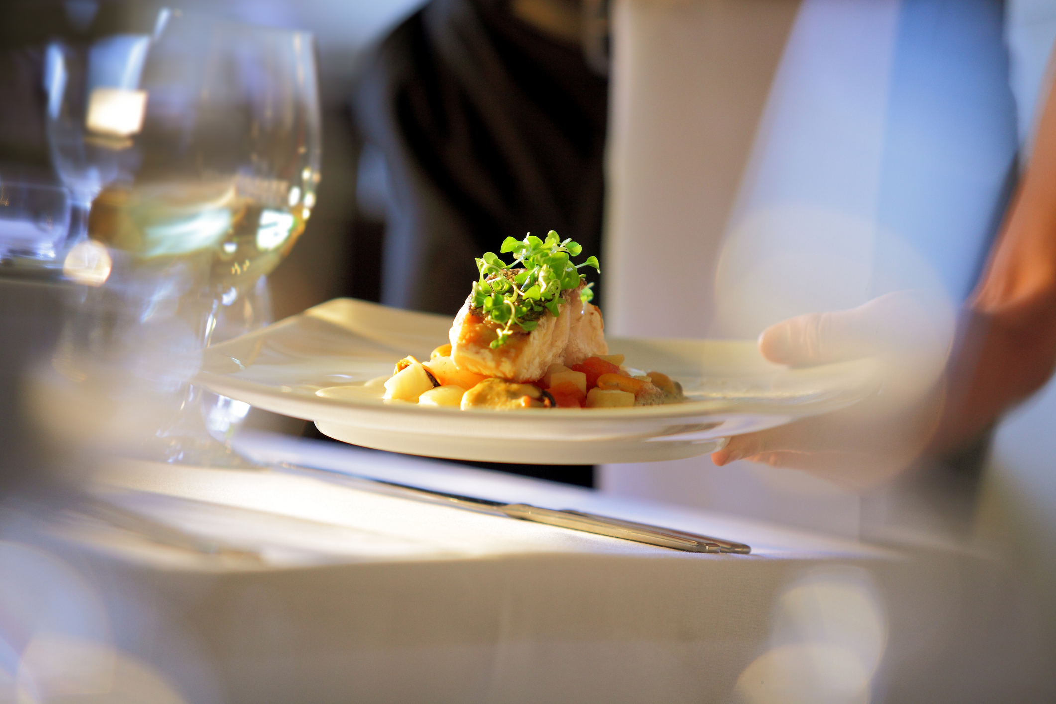 Waiter serving meal at table